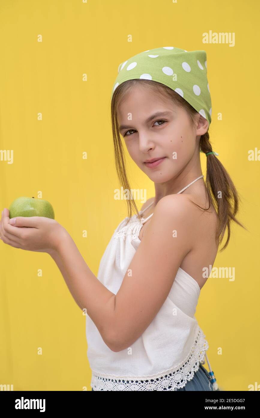 Portrait of a girl wearing a green polka dot headscarf holding a green apple Stock Photo