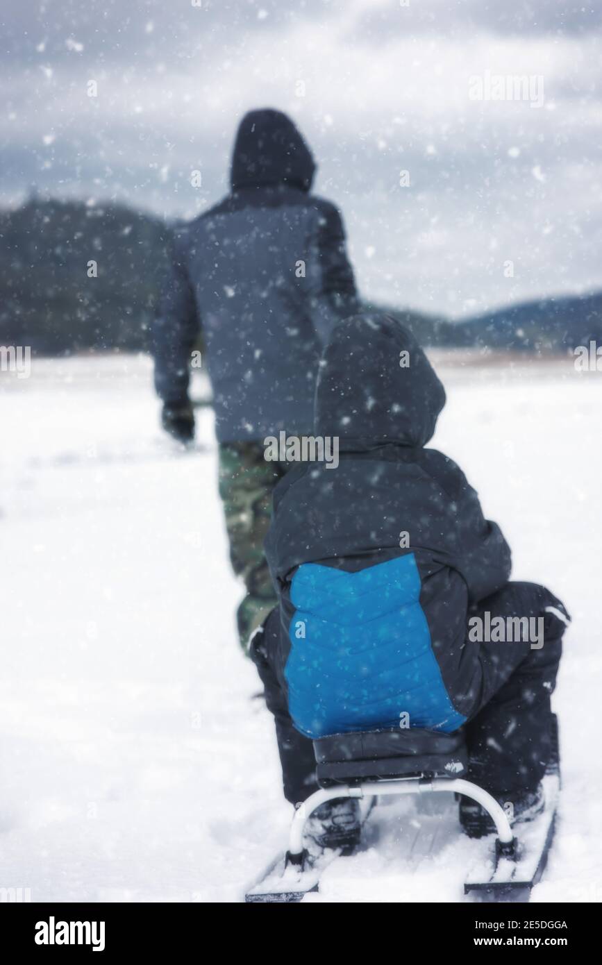 Rear view of a Man pulling a child on a sledge, Bulgaria Stock Photo