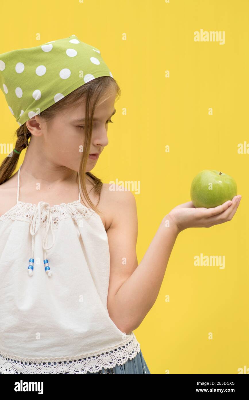 Portrait of a girl wearing a green polka dot headscarf holding a green apple Stock Photo