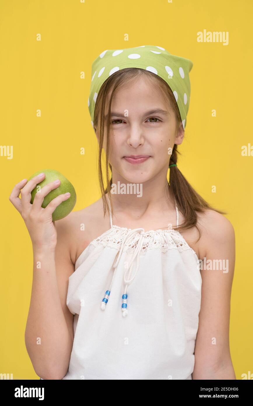 Portrait of a smiling girl wearing a green polka dot headscarf holding a green apple Stock Photo