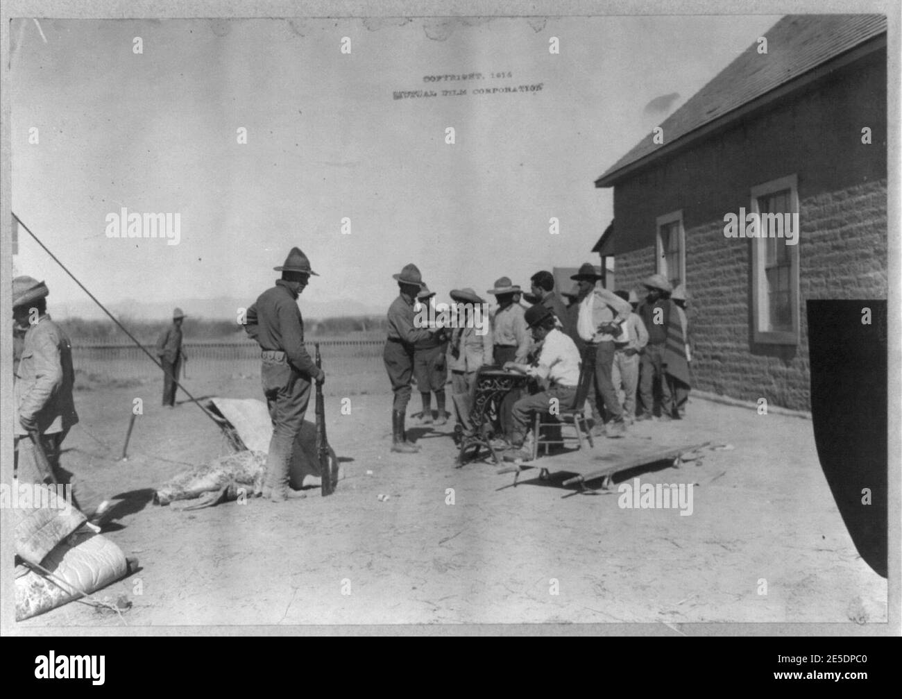 Mexican War, 1914- U.S. soldiers interviewing Mexican refugees; man wearing bowler hat and Red Cross armband seated in center Stock Photo