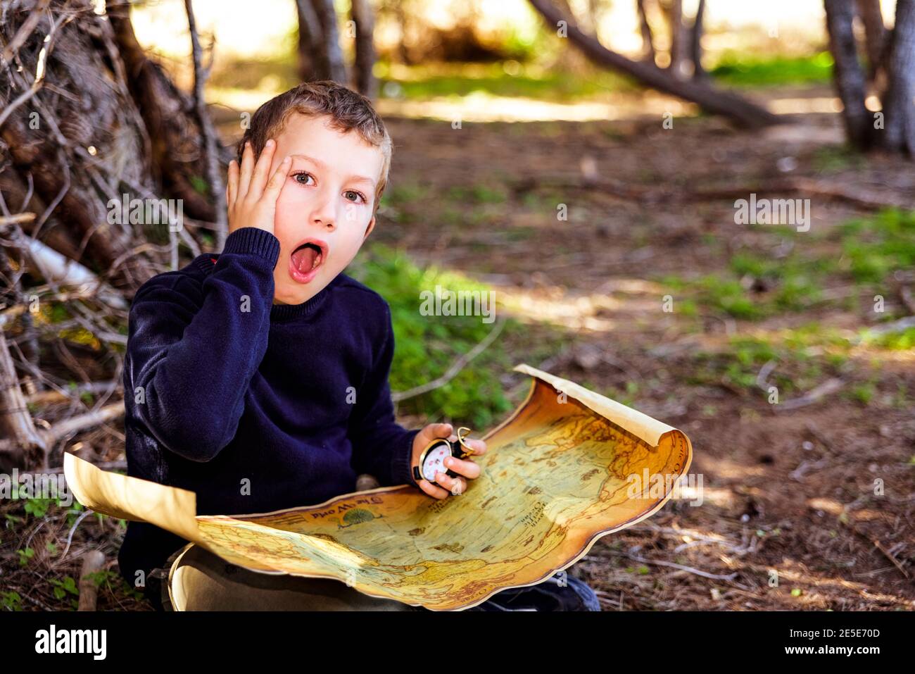 A clever boy searches an ancient map for something buried in a forest