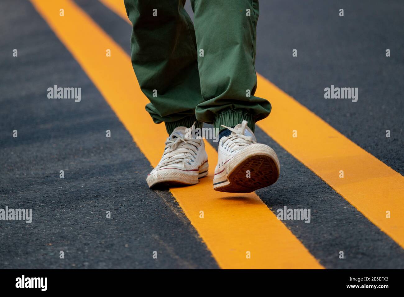 Men wearing sneakers walking on the streets with yellow lines Stock Photo -  Alamy