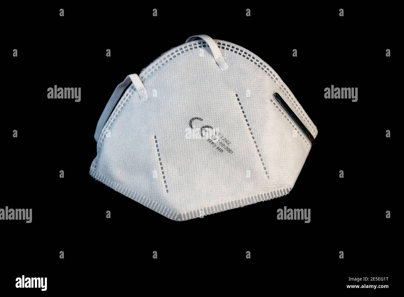 FFP2 face mask in white in front of a clean black background. Certified disposable protection to reduce aerosol emission during Covid-19 pandemic. Stock Photo