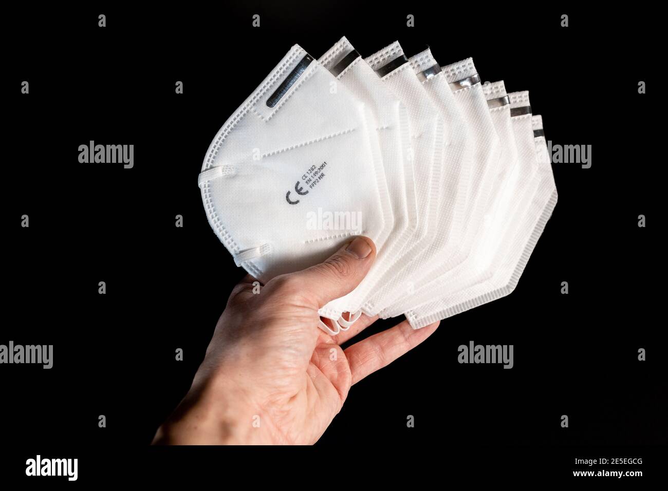Holding many white new FFP2 masks in the hand and looking on it. Certified disposable protection to reduce aerosol emission during Covid-19 pandemic Stock Photo