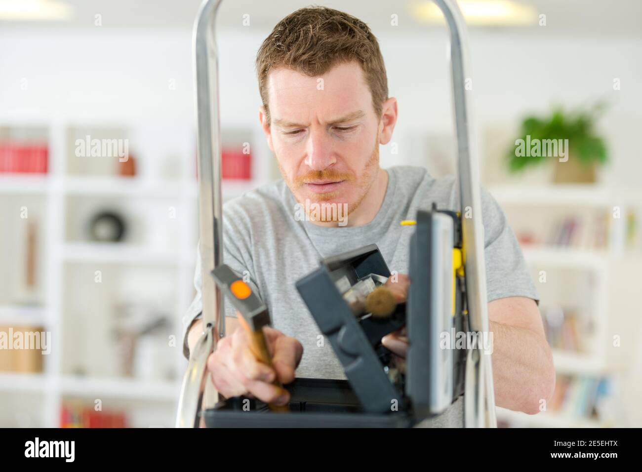 man looking in toolbox on stepladder Stock Photo