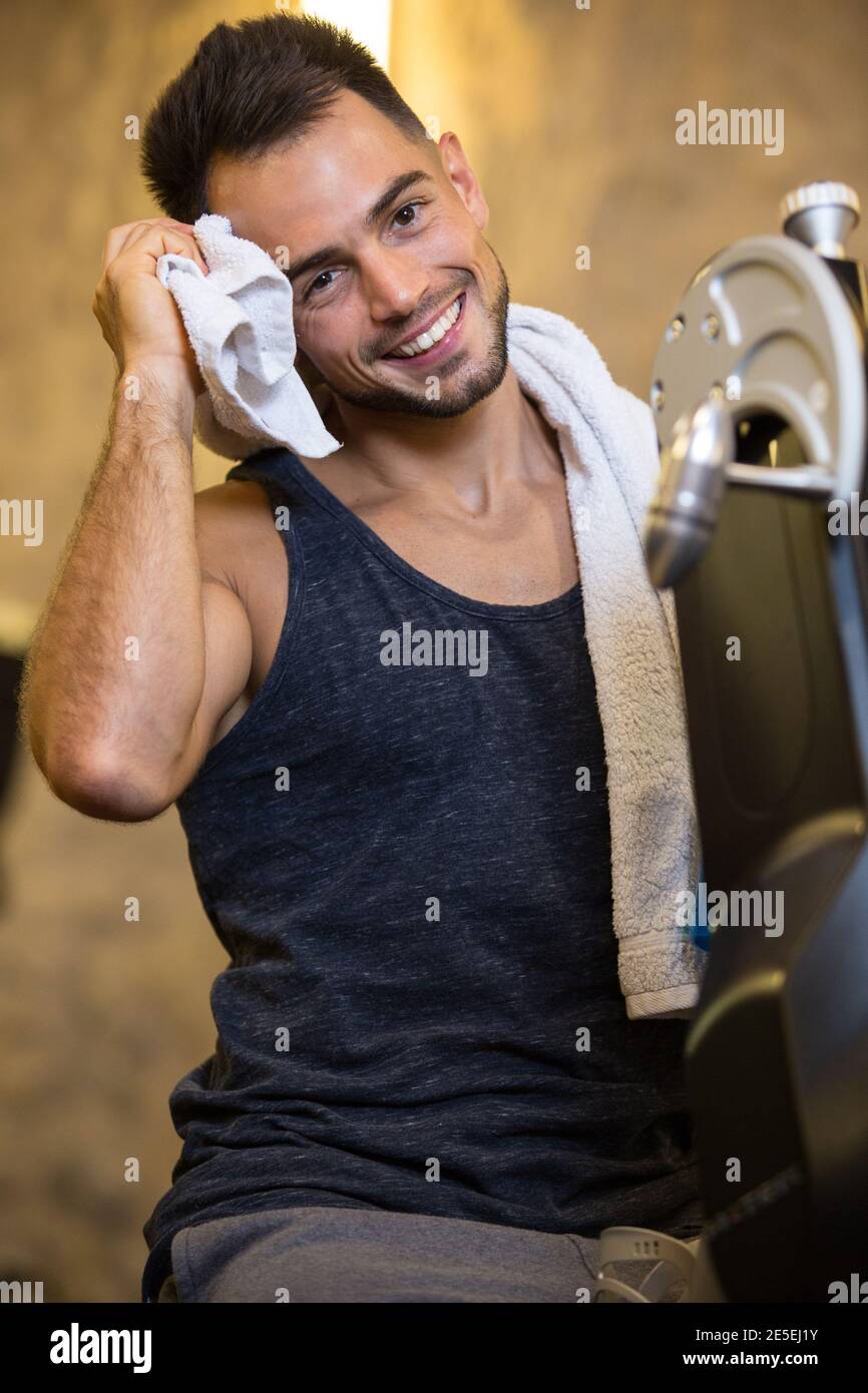 Sweaty after great work out. Handsome young men in sportswear whipping  sweat with his towel and holding water bottle while sitting at gym 13487667  Stock Photo at Vecteezy