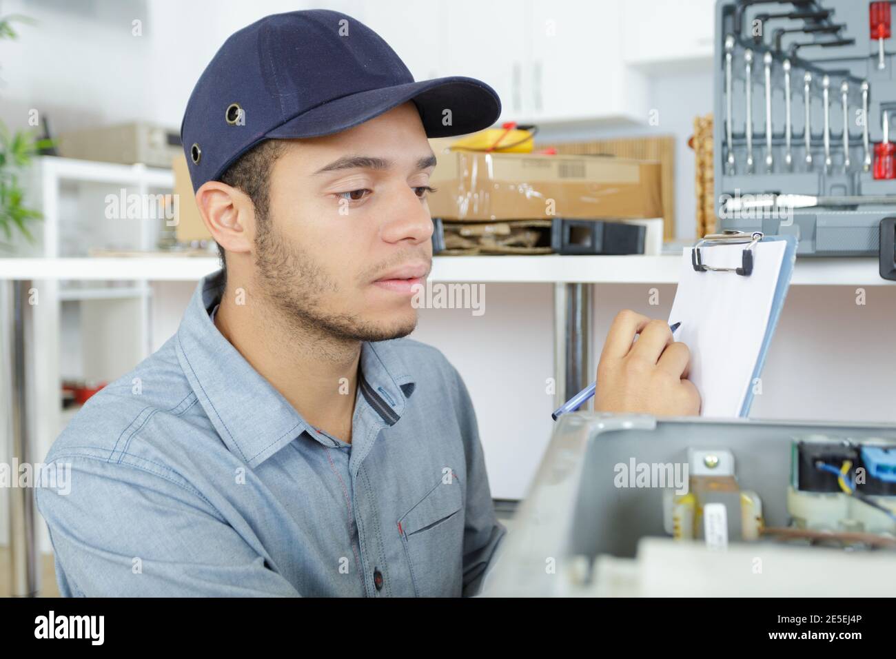 male technician writing on clipboard in kitchen Stock Photo