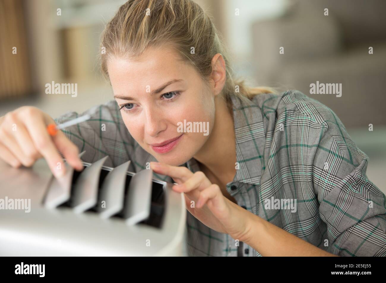 young woman checking air conditioning system Stock Photo