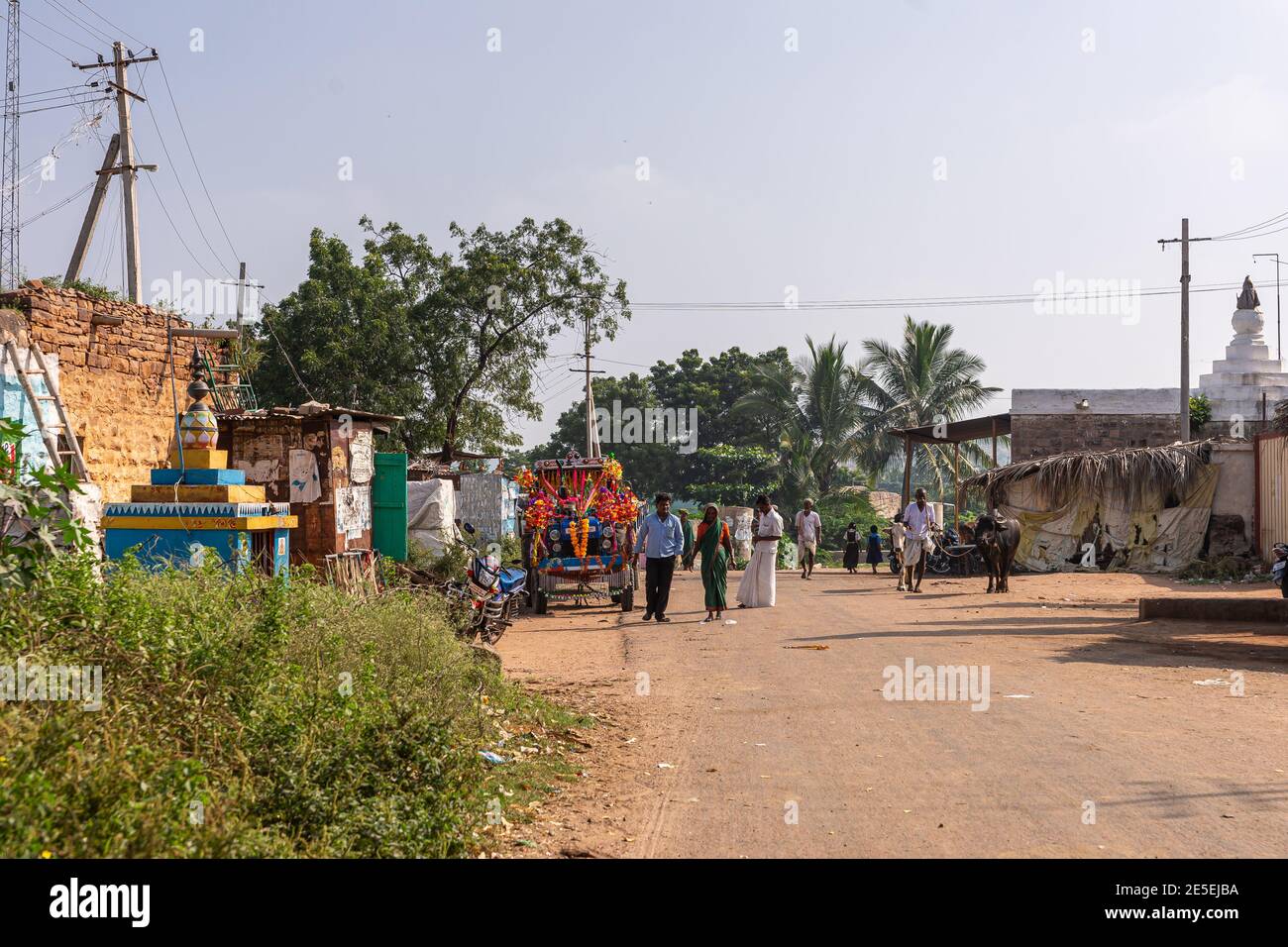Siddanakolla, Karnataka, India - November 7, 2013: Main street through village with walking people and buffalo. Shrine and humble dwellings on side un Stock Photo