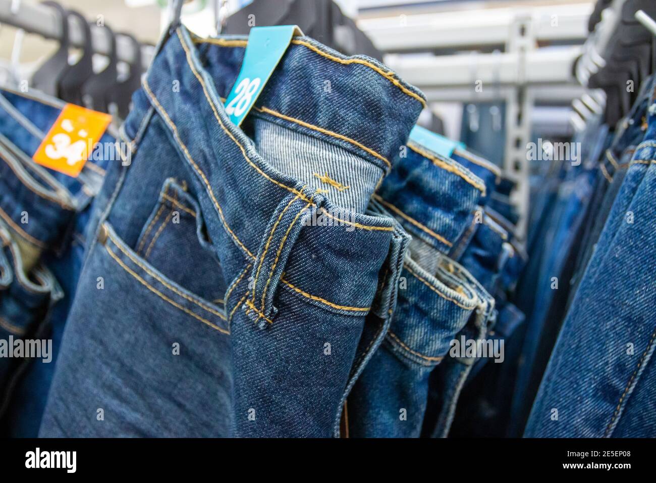 Closeup many jeans hanging on a rack. Row of pants denim jeans hanging