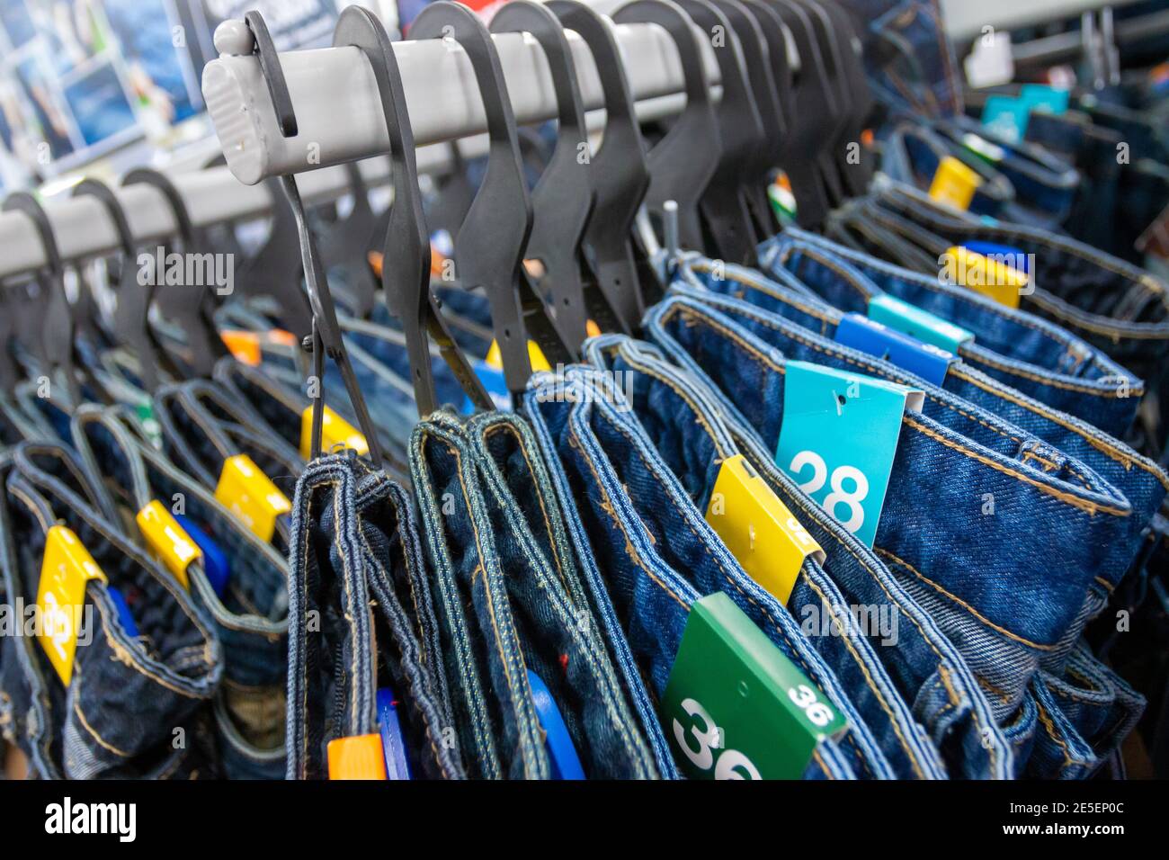 Closeup many jeans hanging on a rack. Row of pants denim jeans hanging