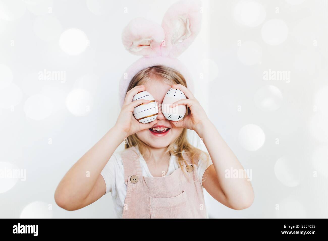 Little girl with Easter eggs and bunny ears hat. Blurred background Stock Photo