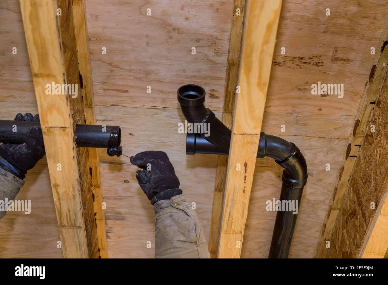 Worker is using glue with fitting for installing the PVC drain pipe in