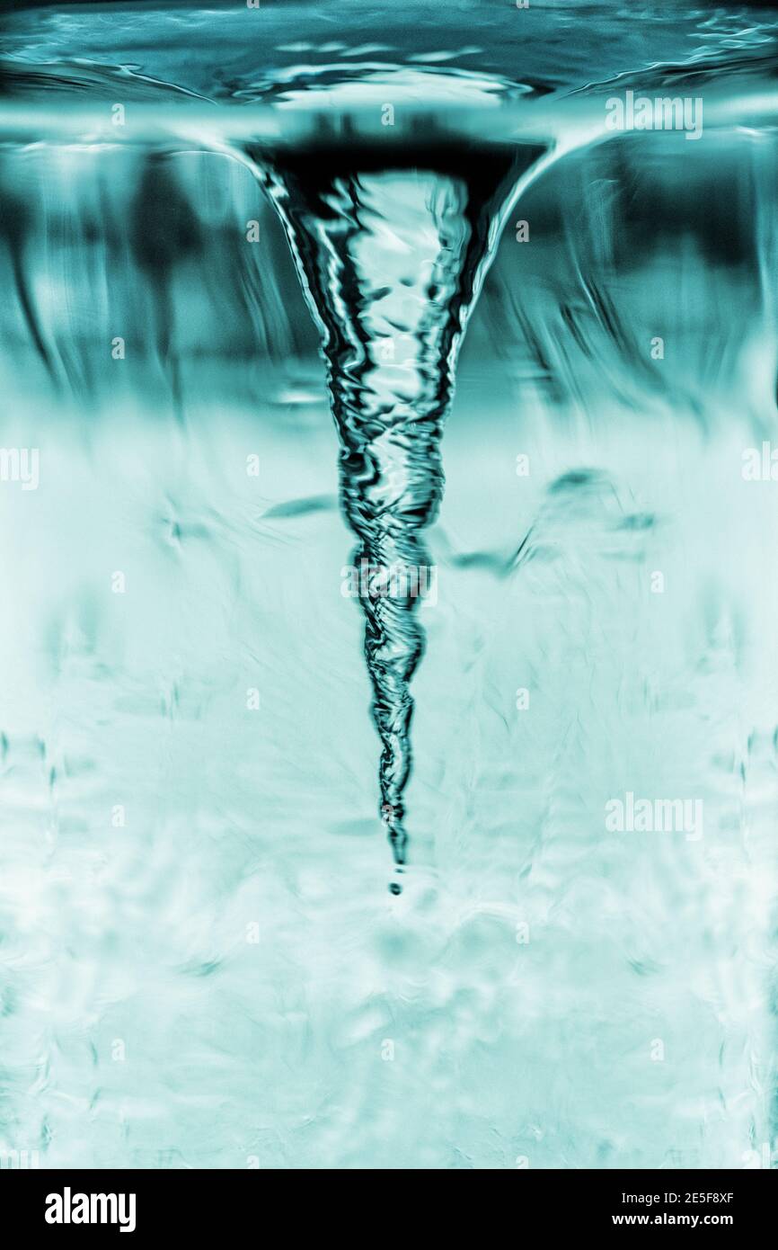 Cyclone demonstration in glass tube, tornado in blue water glass with rotating column of air, water tube with blue whirlpool Stock Photo