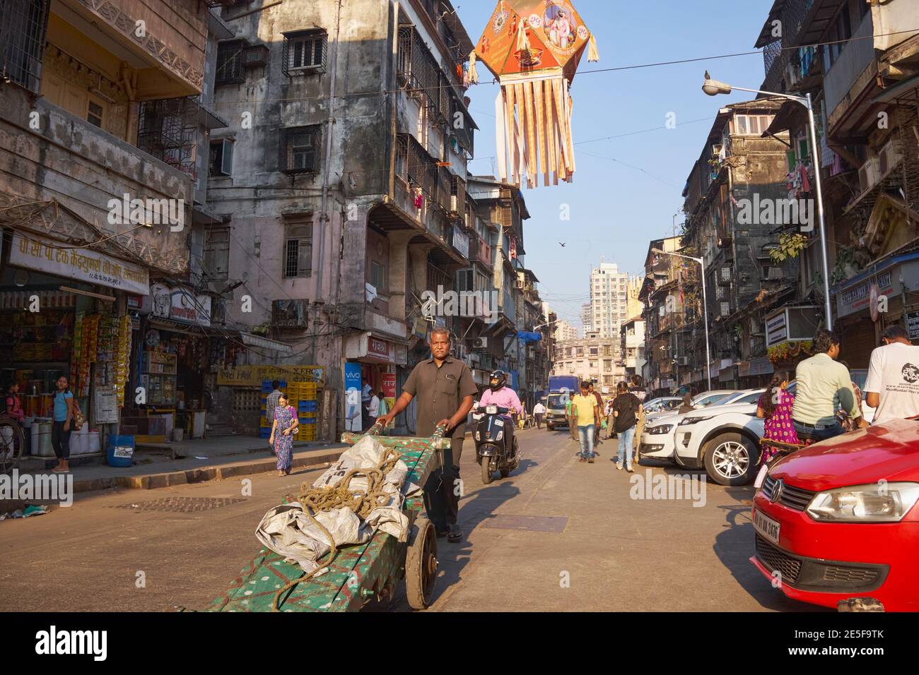 A man pushes his cart across a street in Mumbai, India; carts like his are often used to transport goods through the streets % narrow lanes of Mumbai Stock Photo