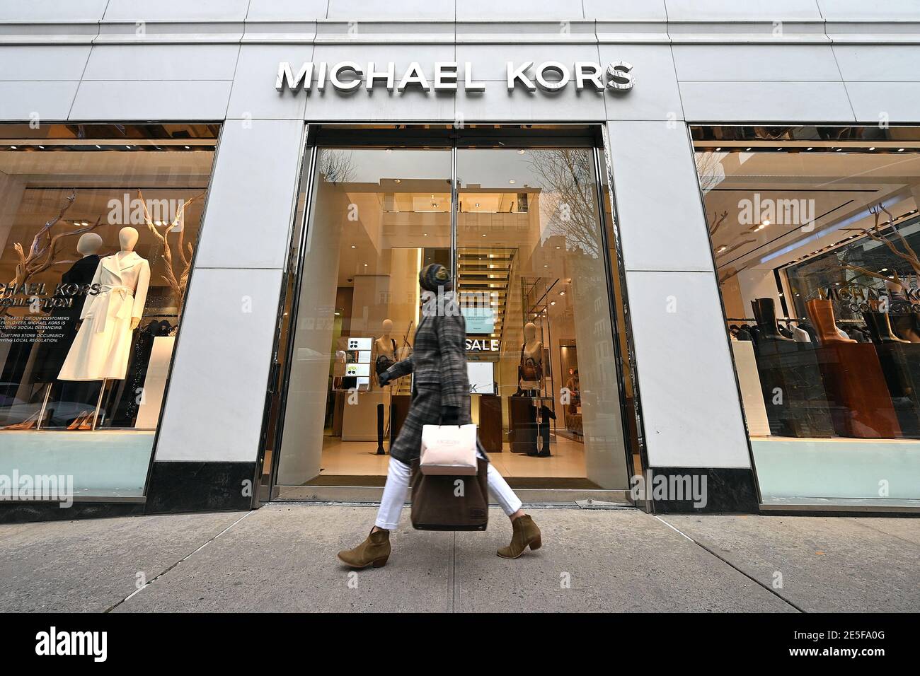 New York, USA. 27th Jan, 2021. A woman walks past the Michael Kors retail  store on Madison Avenue in New York, NY, January 27, 2021. Fashion Week  2021 has started in Paris,