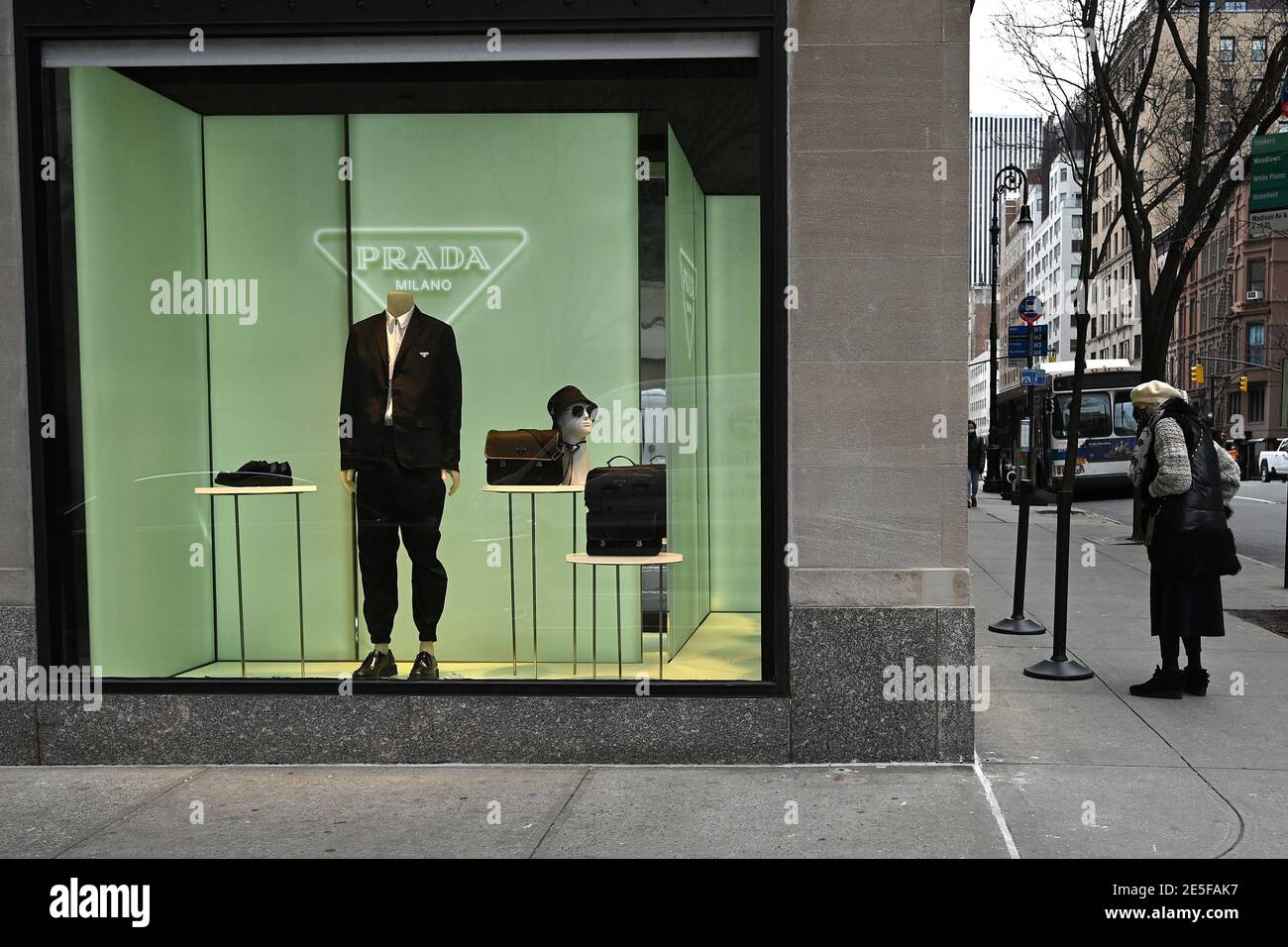 New York, USA. 27th Jan, 2021. A woman wearing a protective face masks  looks at the fashion on display in the window of the Prada Madison Avenue  boutique in New York, NY,