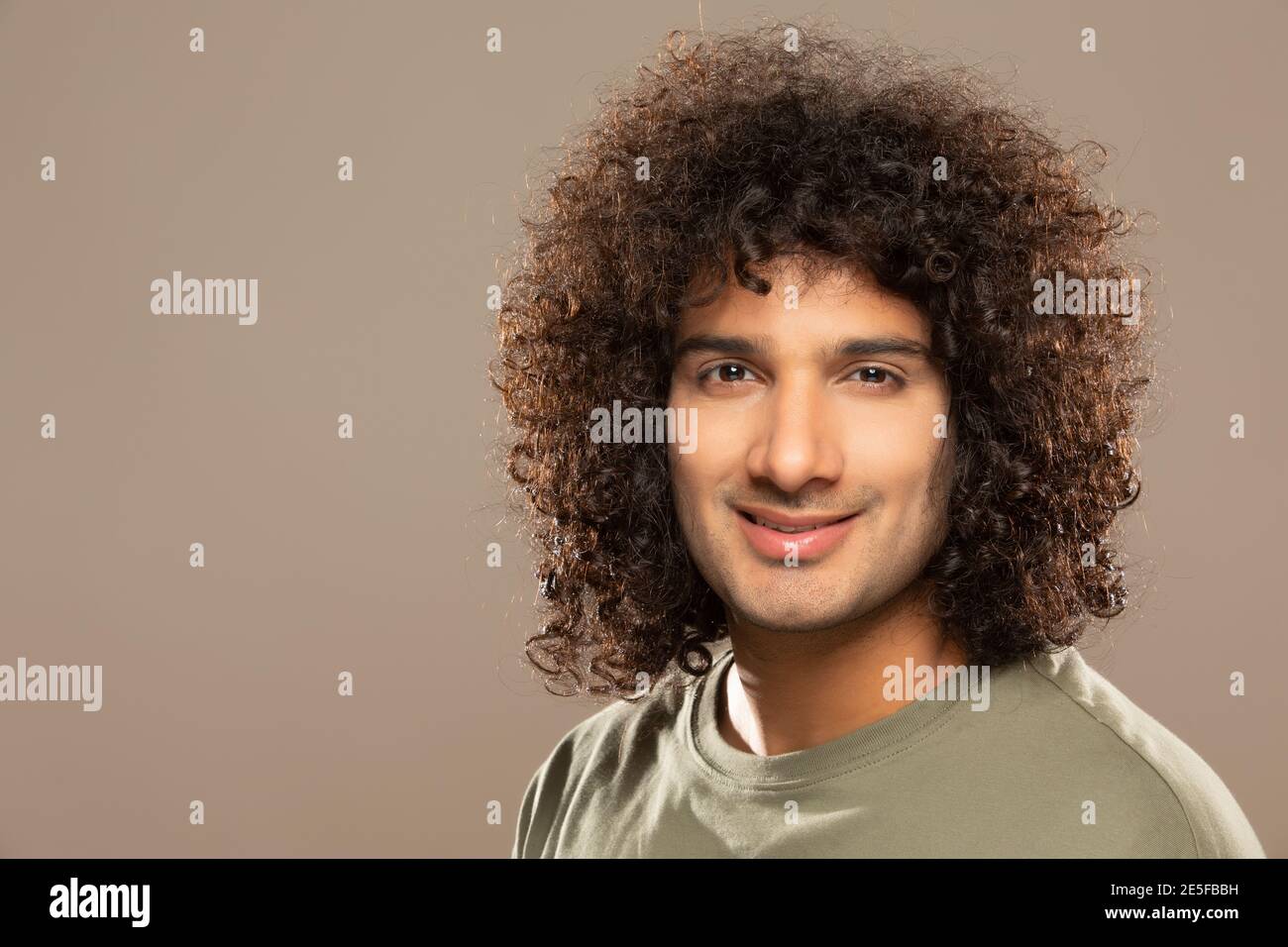 A YOUNG MAN WITH CURLY HAIR LOOKING AT CAMERA AND POSING Stock Photo ...