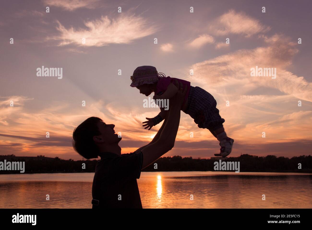 Father and little daughter silhouettes at sunset Stock Photo