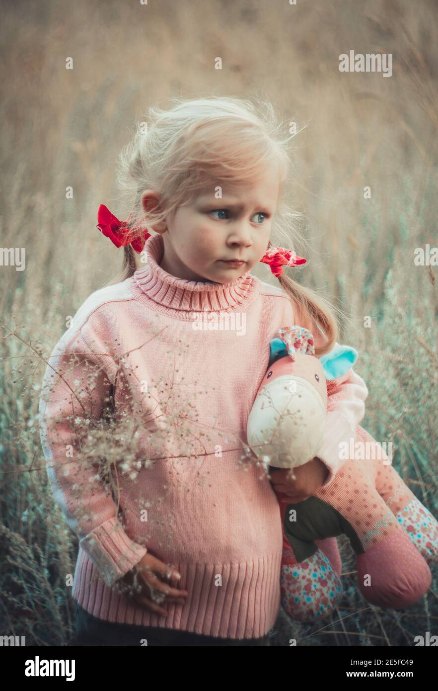 Adorable sad girl with hourse toy in park Stock Photo