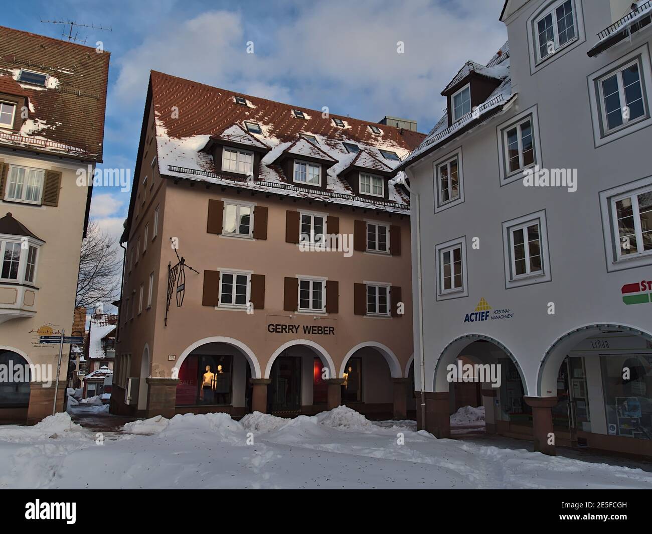 Corner of historic snow-covered market place of Freudenstadt, Black Forest with old buildings, arcades and shops including a Gerry Weber branch. Stock Photo