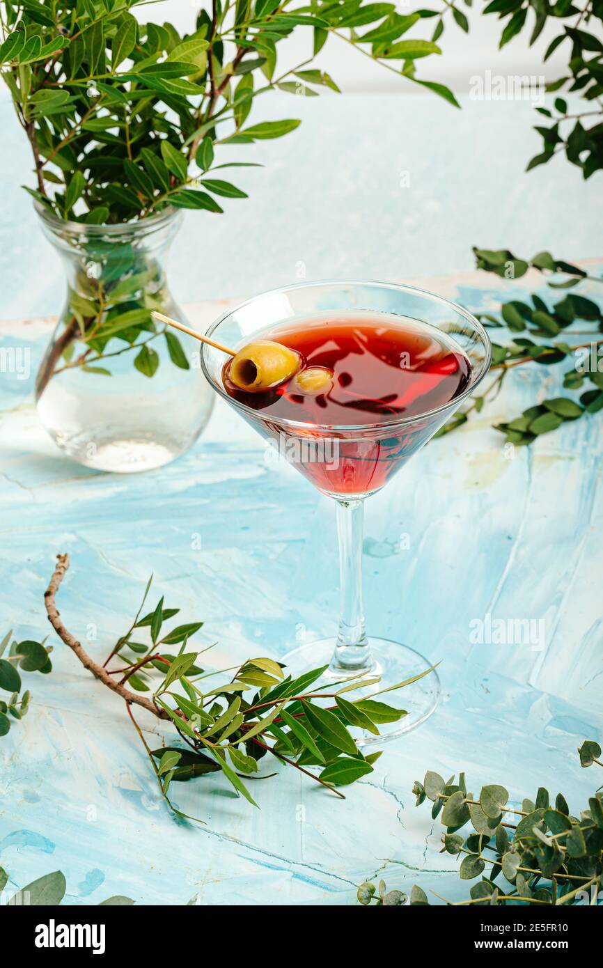 Martini glass with red alcohol cocktail and olives Stock Photo