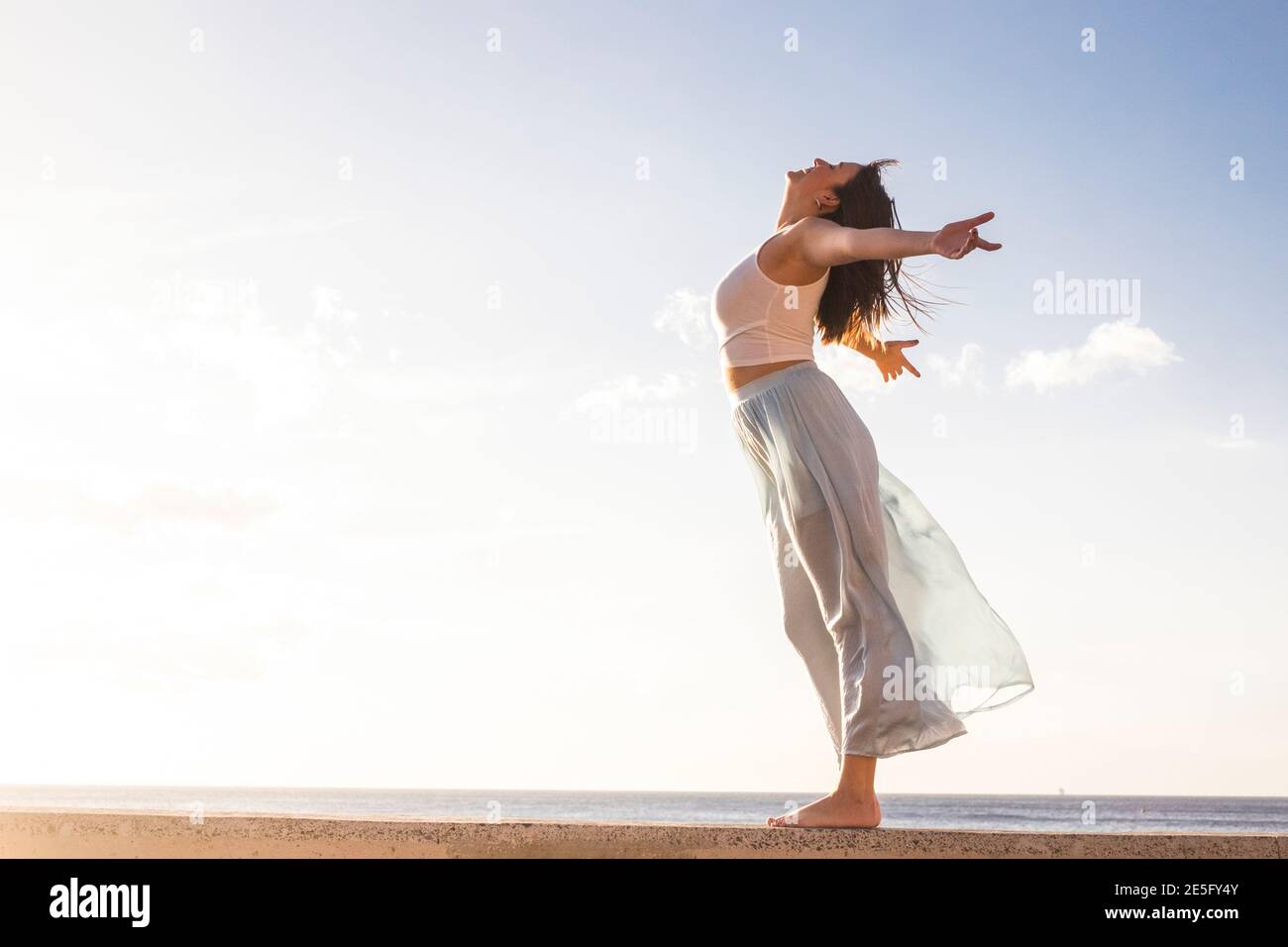 Freedom and empowerment female concept with young girl standing and enjoying outdoor nature - young girl love free independent life and vacation - sky Stock Photo