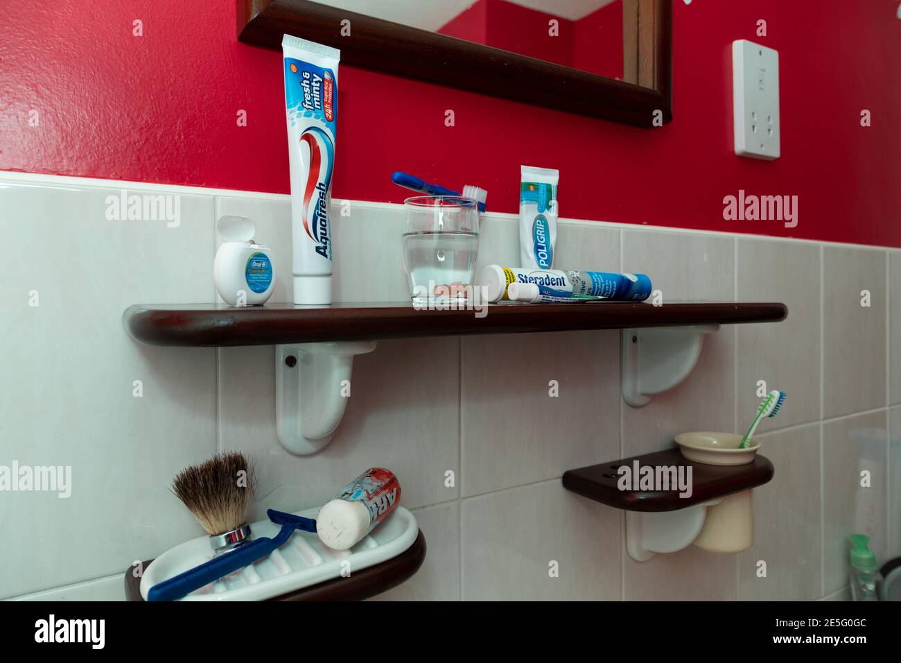 Oral health products and dental fixative products on a bathroom shelf. Stock Photo