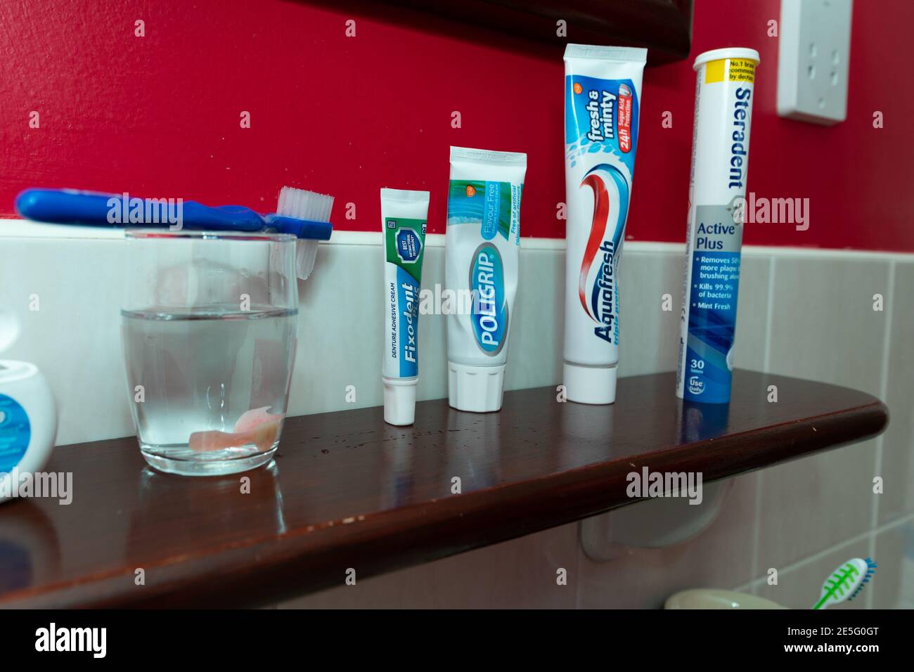 Oral health products and dental fixative products on a bathroom shelf. Stock Photo