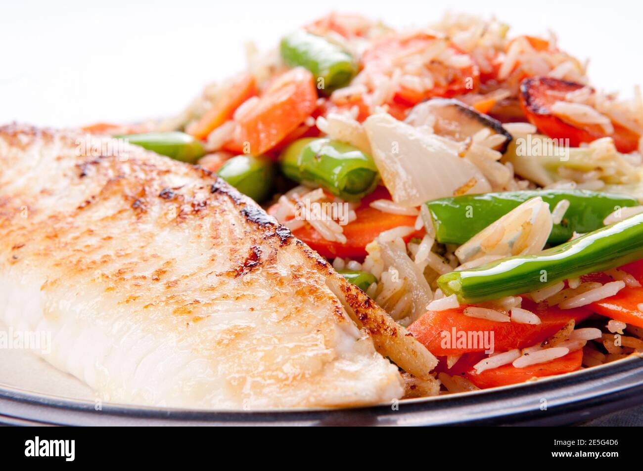 seared tilapia fish filet with rice stir fry Stock Photo Alamy