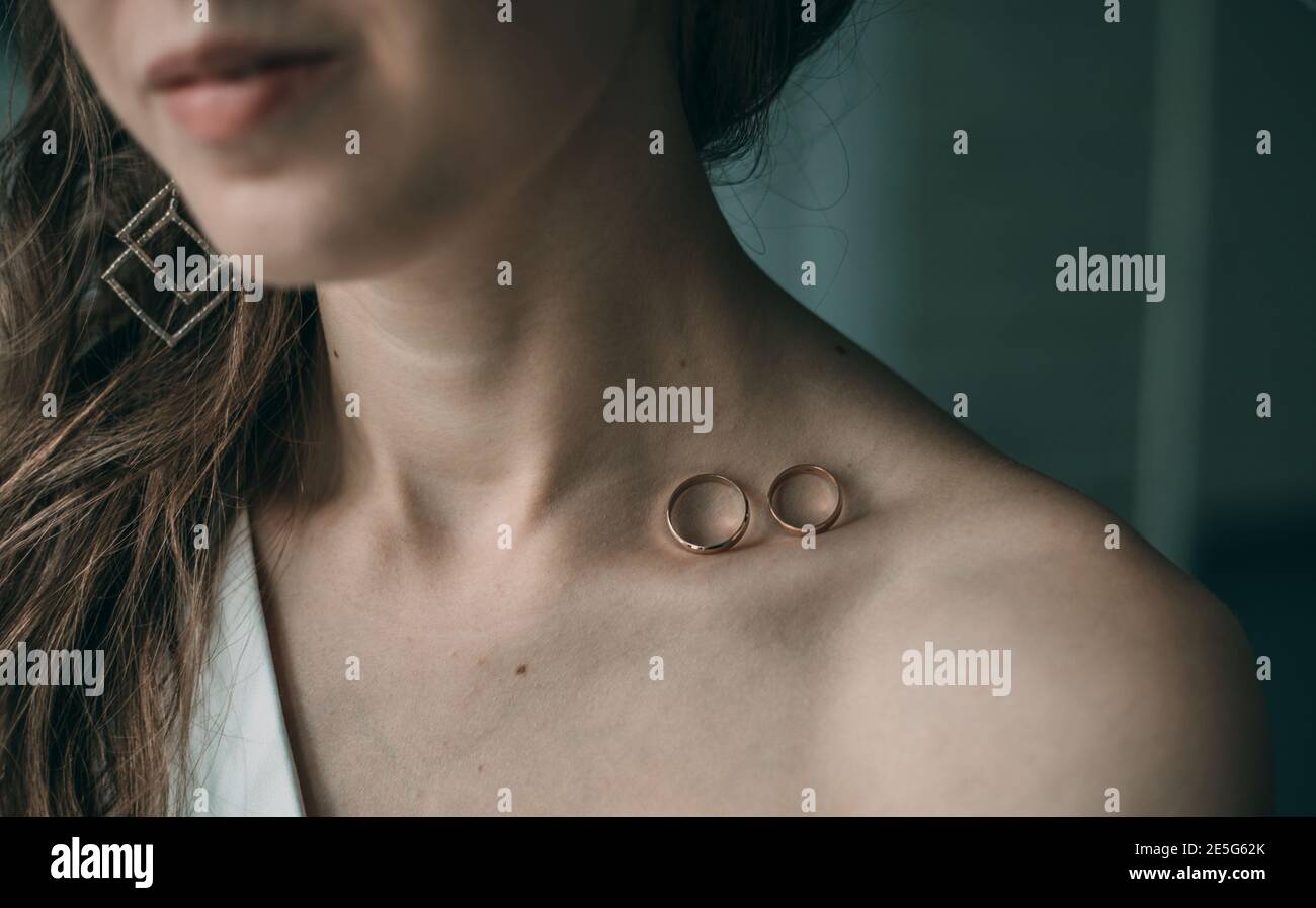 Wedding rings on the bride's collarbone. The concept of celebrating Valentine's Day Stock Photo