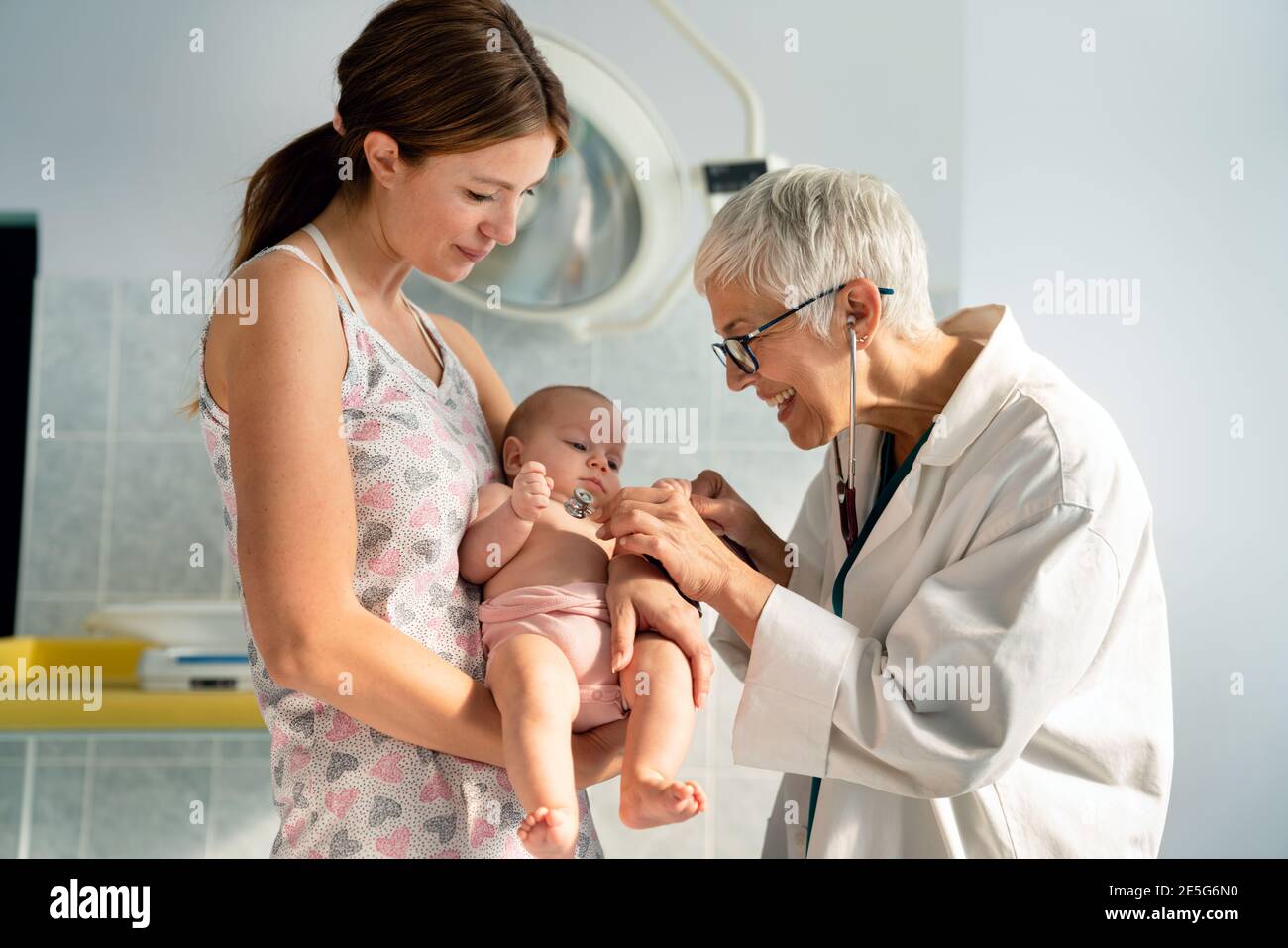 Mother holding baby for pediatrician doctor to examine Stock Photo