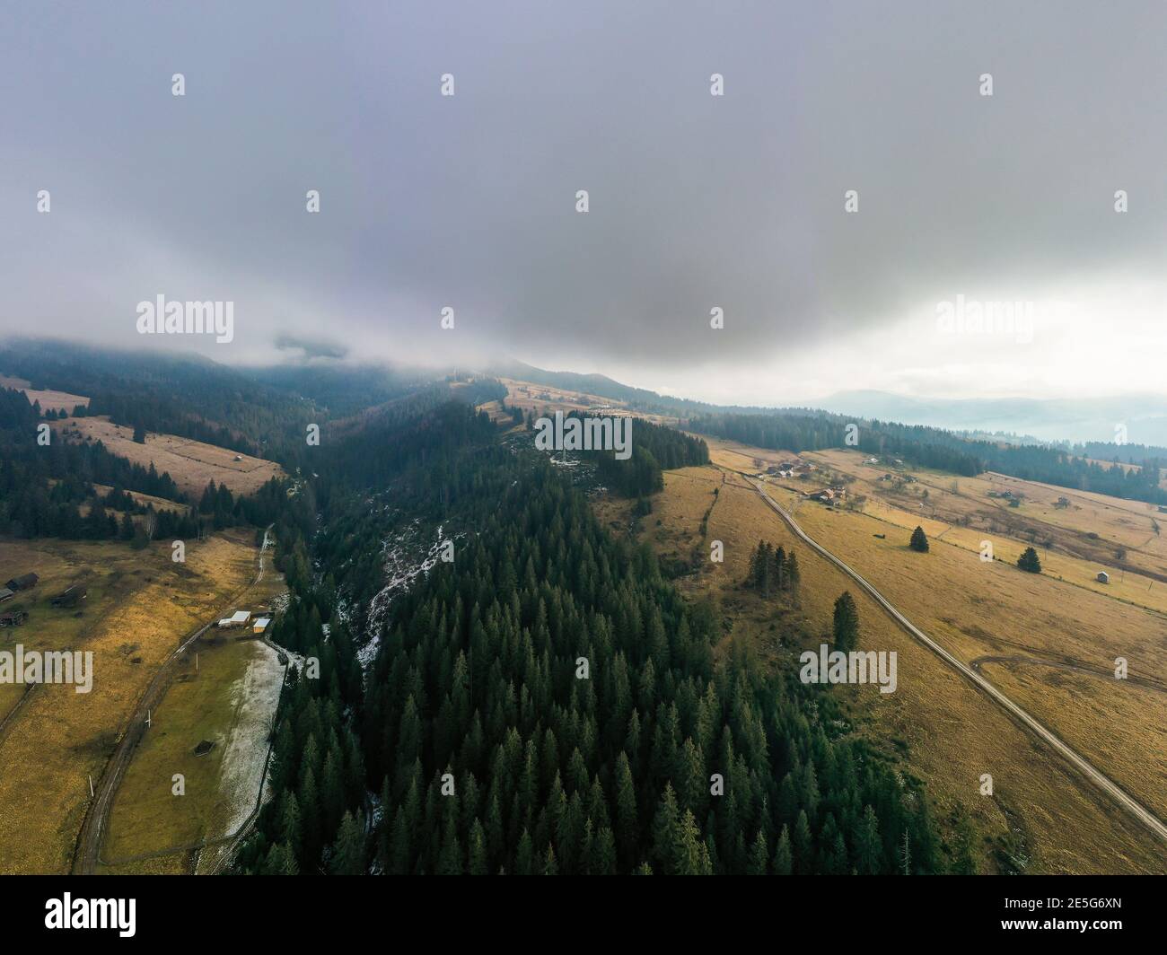 Small village in a mountain valley of the Carpathian Mountains on an autumn day in Ukraine in the village of Dzembronya. Aerial panoramic drone shot Stock Photo