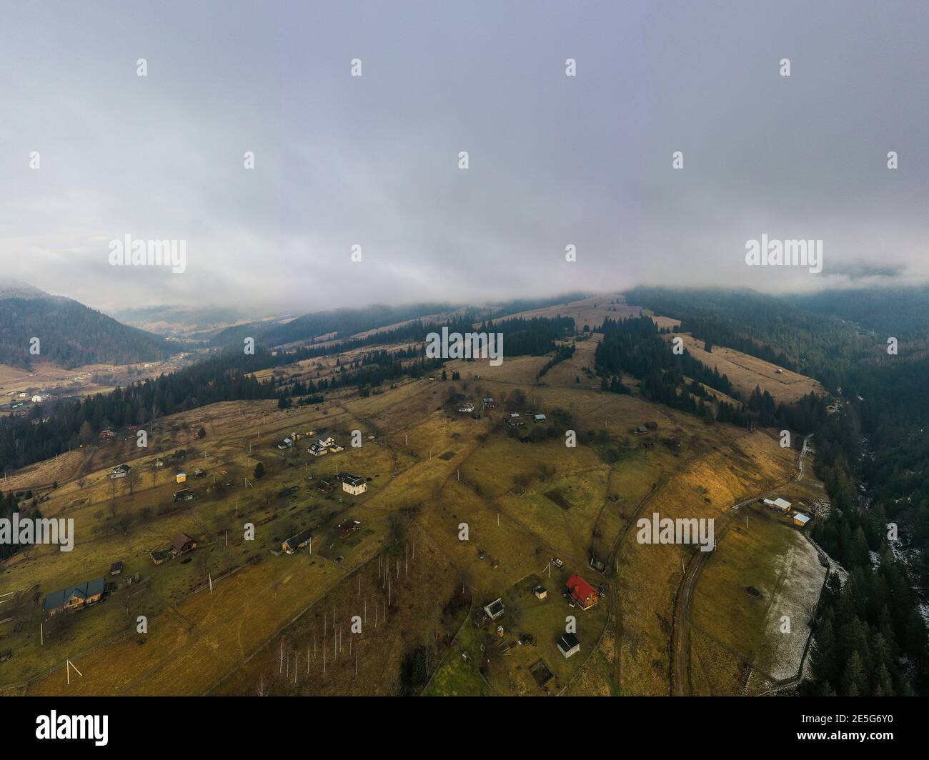 Small village in a mountain valley of the Carpathian Mountains on an autumn day in Ukraine in the village of Dzembronya. Aerial panoramic drone shot Stock Photo