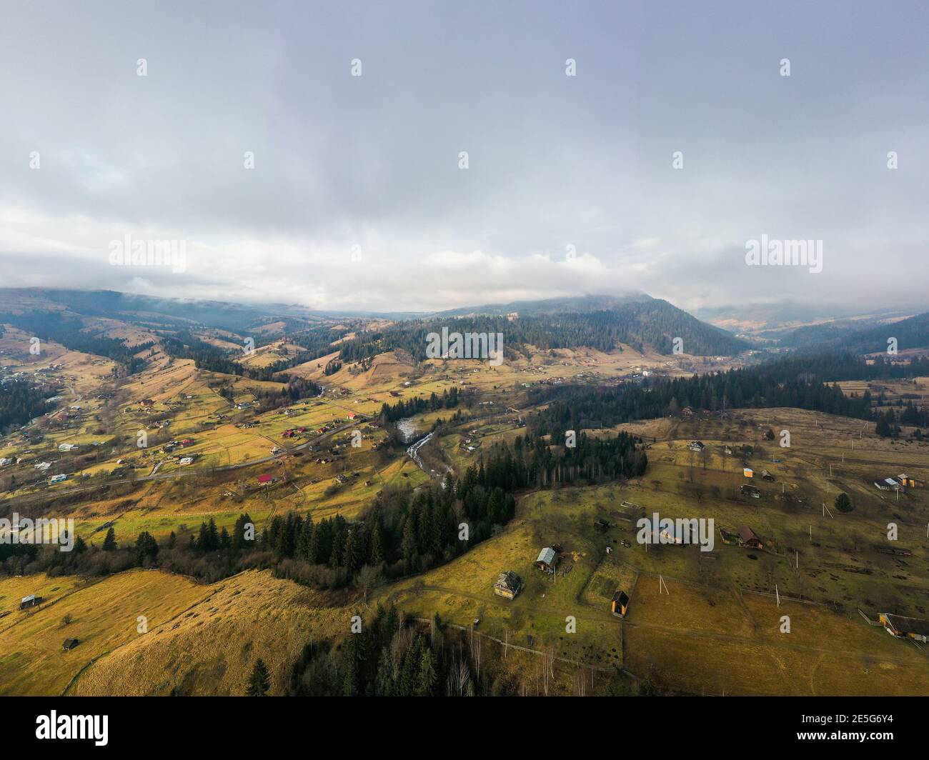 Small village in a mountain valley of the Carpathian Mountains on an autumn day in Ukraine in the village of Dzembronya. Aerial panoramic drone shot Stock Photo