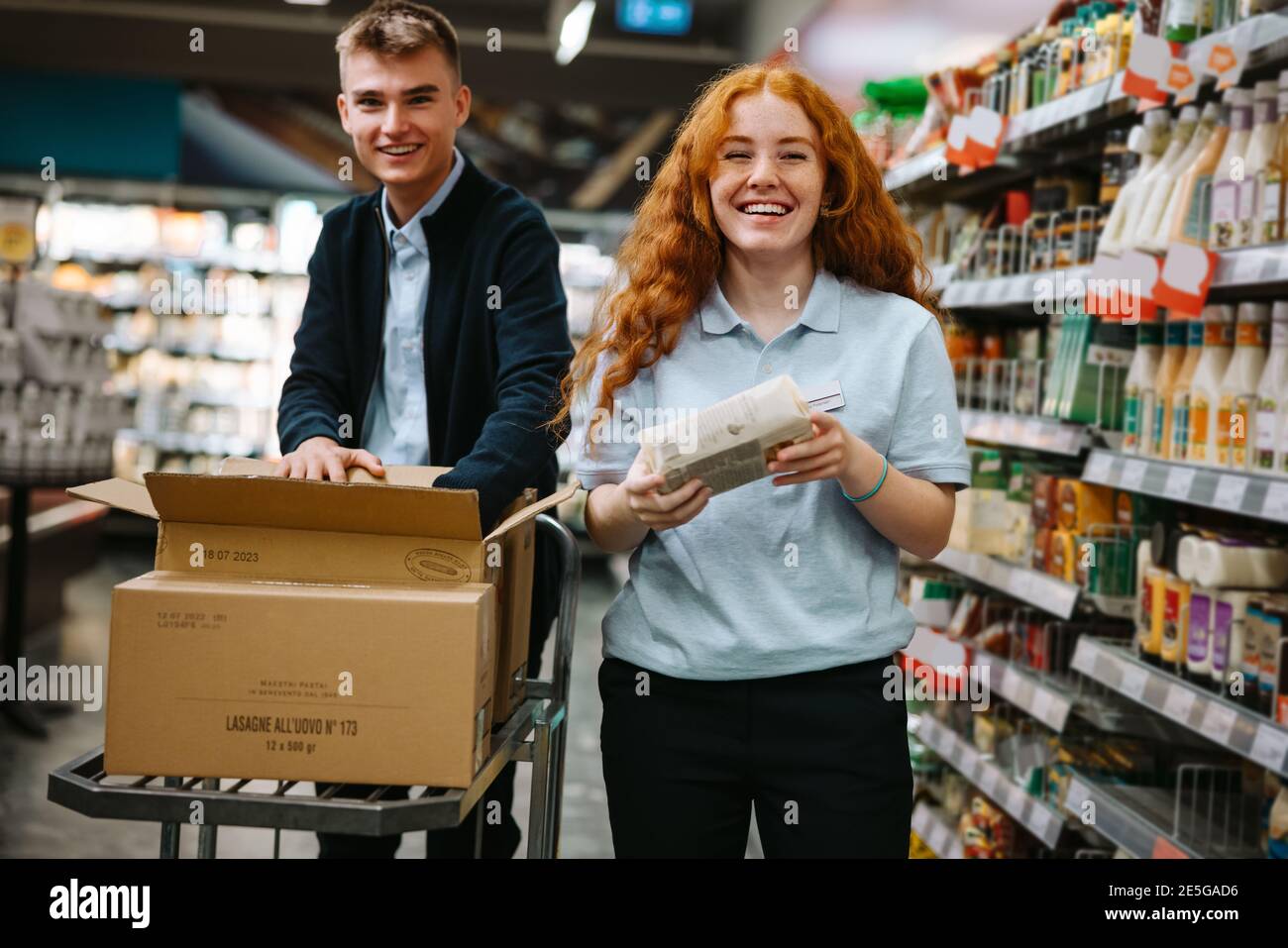 Supermarket employees working in the store. Male and female workers restocking products shelves