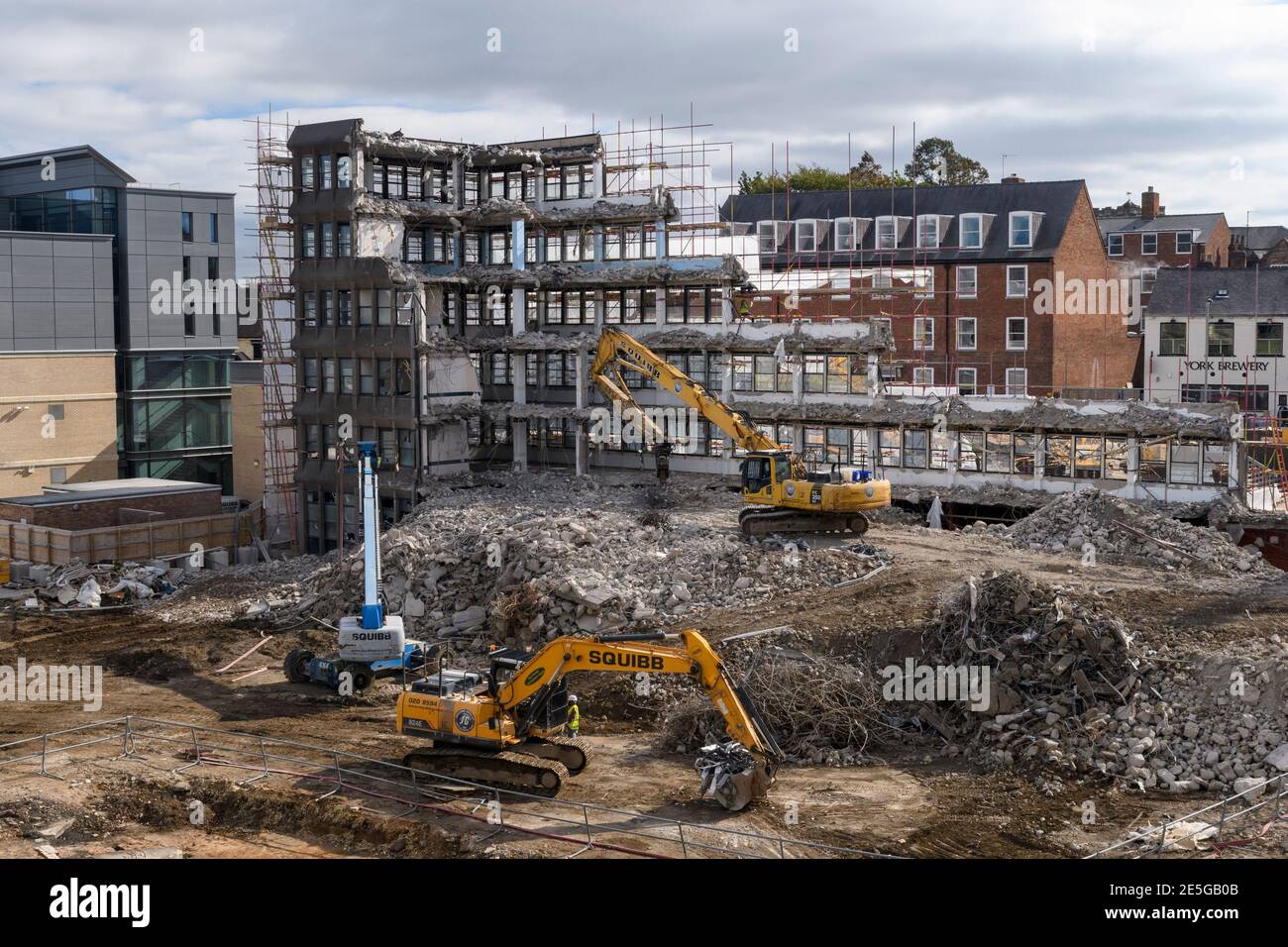 Demolition site high view (rubble, heavy machinery, excavators working & demolishing empty office building shell) - Hudson House, York, England, UK. Stock Photo