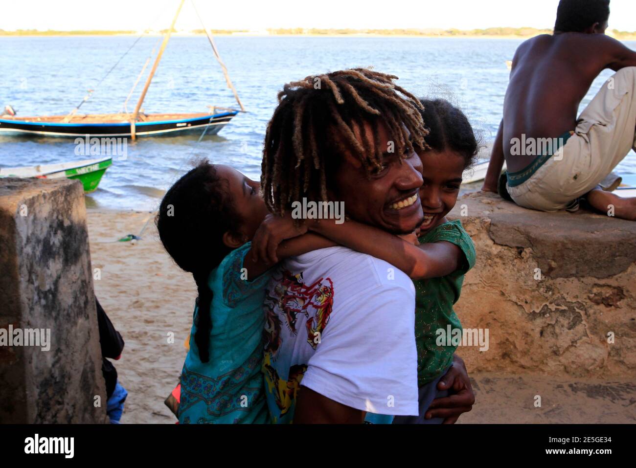 A Kenyan man plays with his daughters on the shores of Shela Island in  Lamu, October 1, 2011, near the beach home of a disabled French woman held  hostage. Kenyan coastguards were