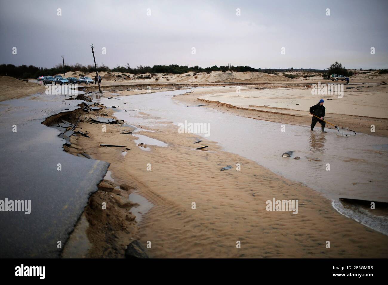 A man searches in a river stream following heavy rains and flooding on a beach of the Mediterranean sea near Kibbutz Nitzanim in southern Israel December 14, 2013. REUTERS/Amir Cohen (ISRAEL - Tags: ENVIRONMENT) Stock Photo