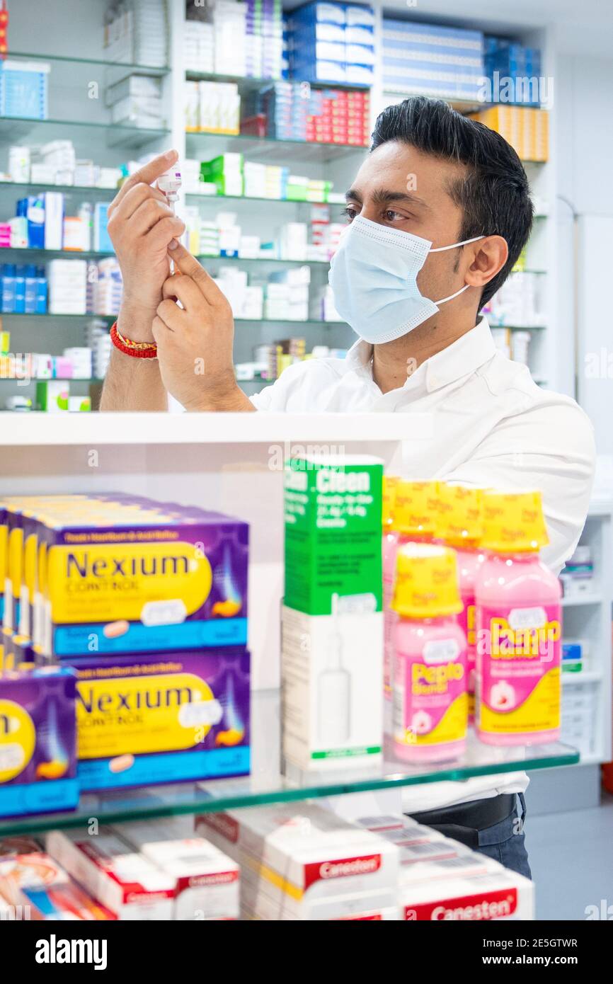 Pharmacist Bhaveen Patel draws up a dose of the Oxford / AstraZeneca covid vaccine in preparation for coronavirus vaccinations during a clinic held at Junction Pharmacy in Brixton, London. The roll out of the vaccination programme continues as the Government targets vaccinating the 15 million in the most vulnerable groups by mid-February. Picture date: Thursday January 28, 2021. Stock Photo
