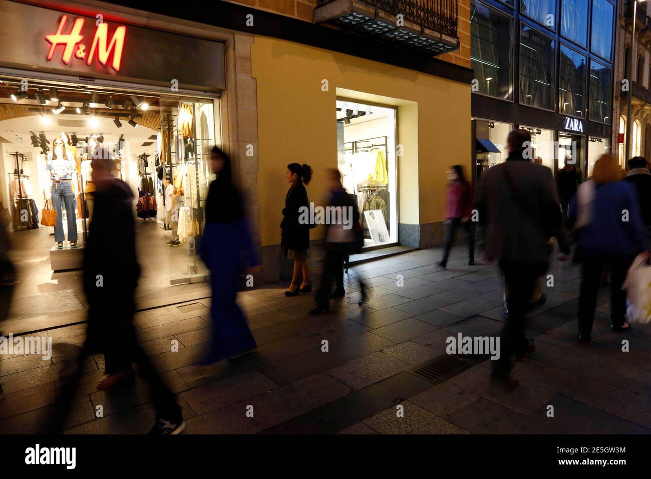 People walk past H&M and Zara stores in central Barcelona March 11, 2015.  The families behind Zara-owner Inditex and H&M will need to fend off  fast-moving competitors if they are to replicate