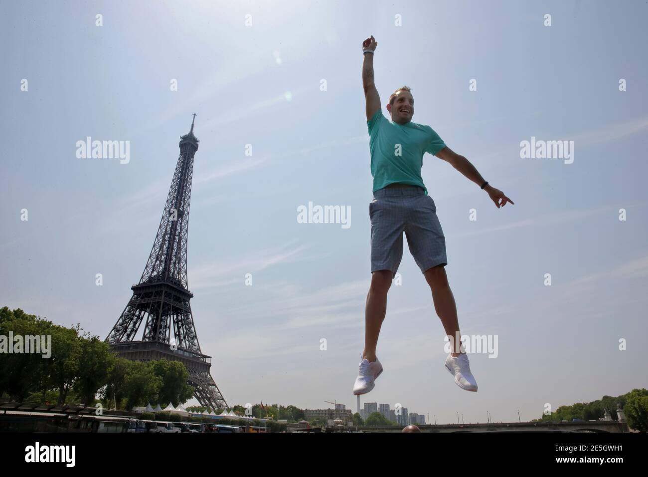 World-record pole vaulter Renaud Lavillenie of France jumps in front of the  Eiffel tower as he stands on the roof of a boat on the Seine River after a  news conference in