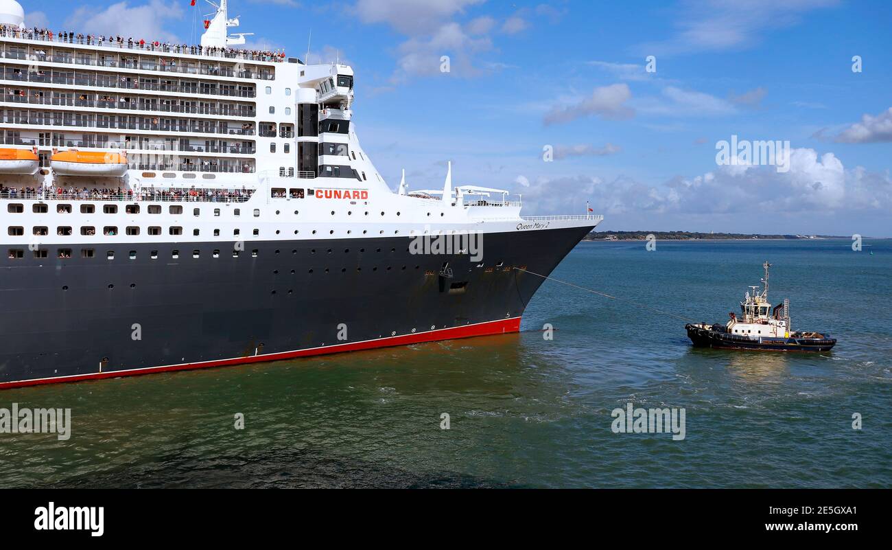 Cunard’s Queen Mary 2 being Tug assisted out of Southampton Cruise Terminal August 2019.... Ahh, those were the days before COVID 19. Stock Photo