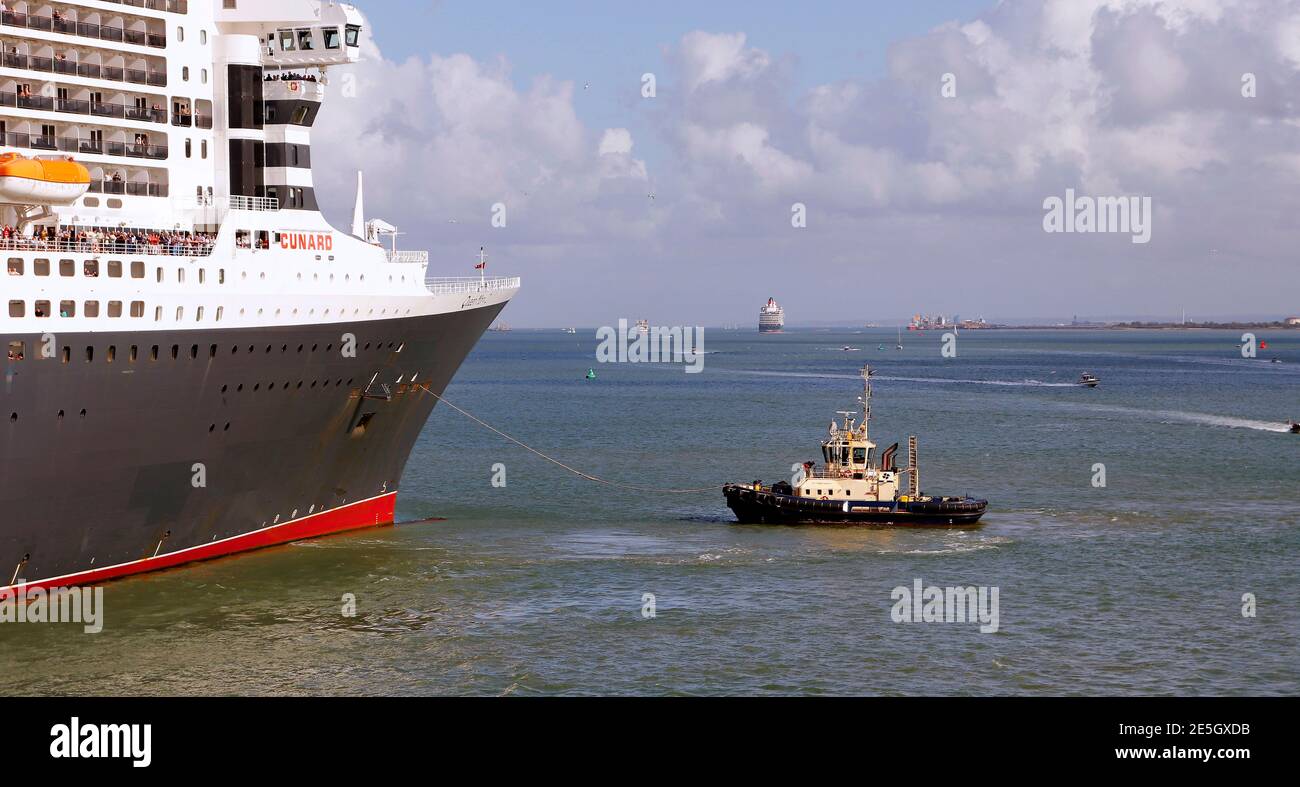 Cunard’s Queen Mary 2 preparing to leave port. Cunard’s Cruise ship Queen Victoria can be seen on the horizon. Stock Photo