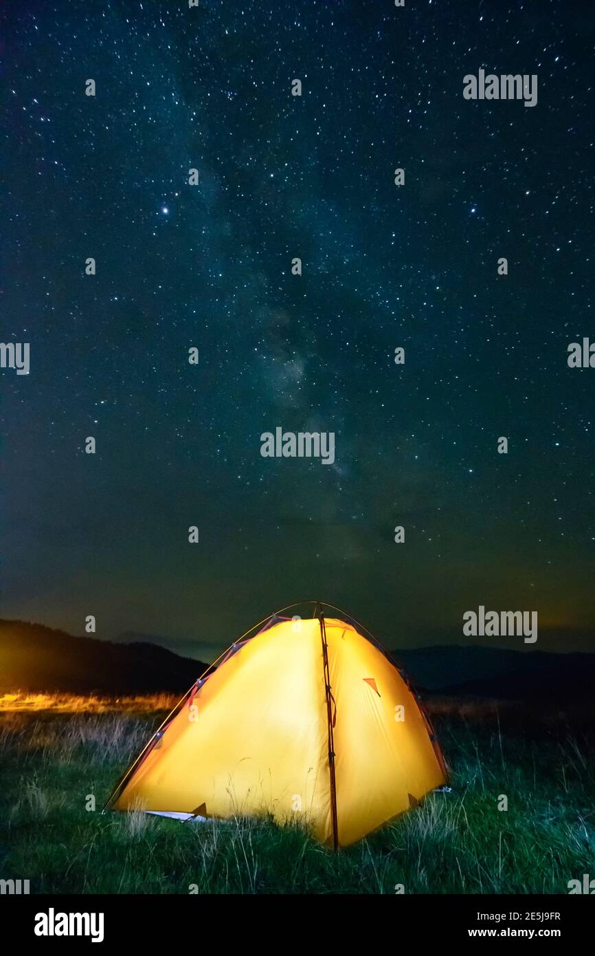 Glowing yellow tent in the mountains under a starry sky Stock Photo - Alamy
