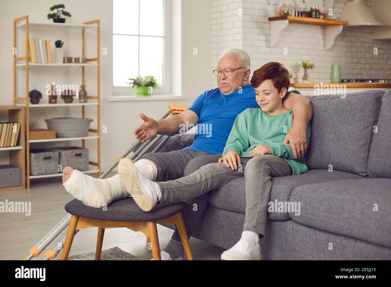 Older man with a broken leg in a plaster cast and tells grandson the story of how he broke ankle. Stock Photo
