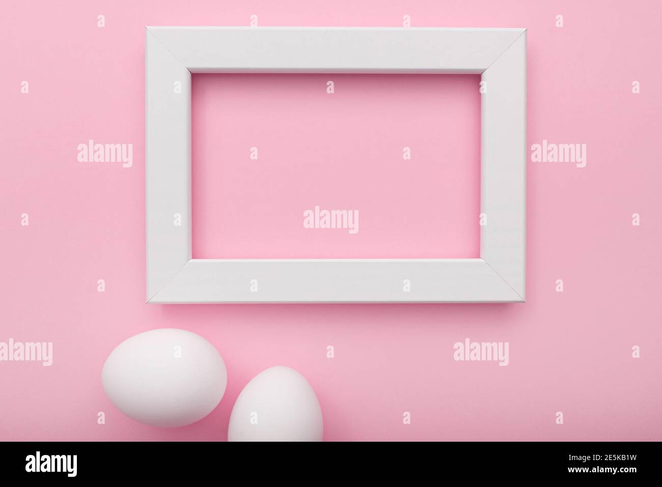 White frame and eggs on pink background, Easter minimal flat lay, top view, space for text Stock Photo