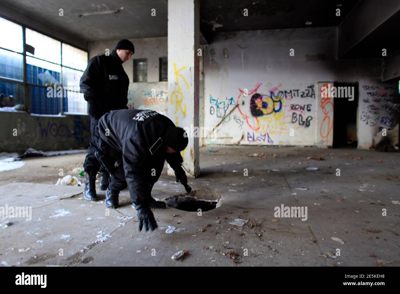 Local policemen look for homeless people inside a run-down building in  Bucharest February 1, 2012. Local police and authorities are trying to  relocate homeless people to community shelters where they can sleep