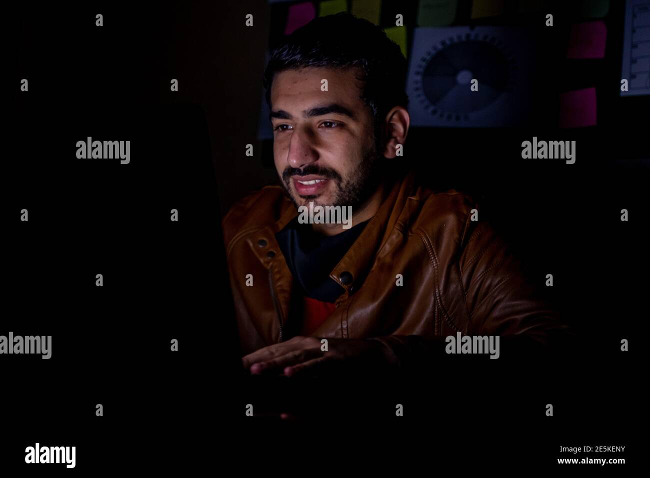 Young man in the overtime in the dark from his office working hard on his project with a smile look on his face Stock Photo
